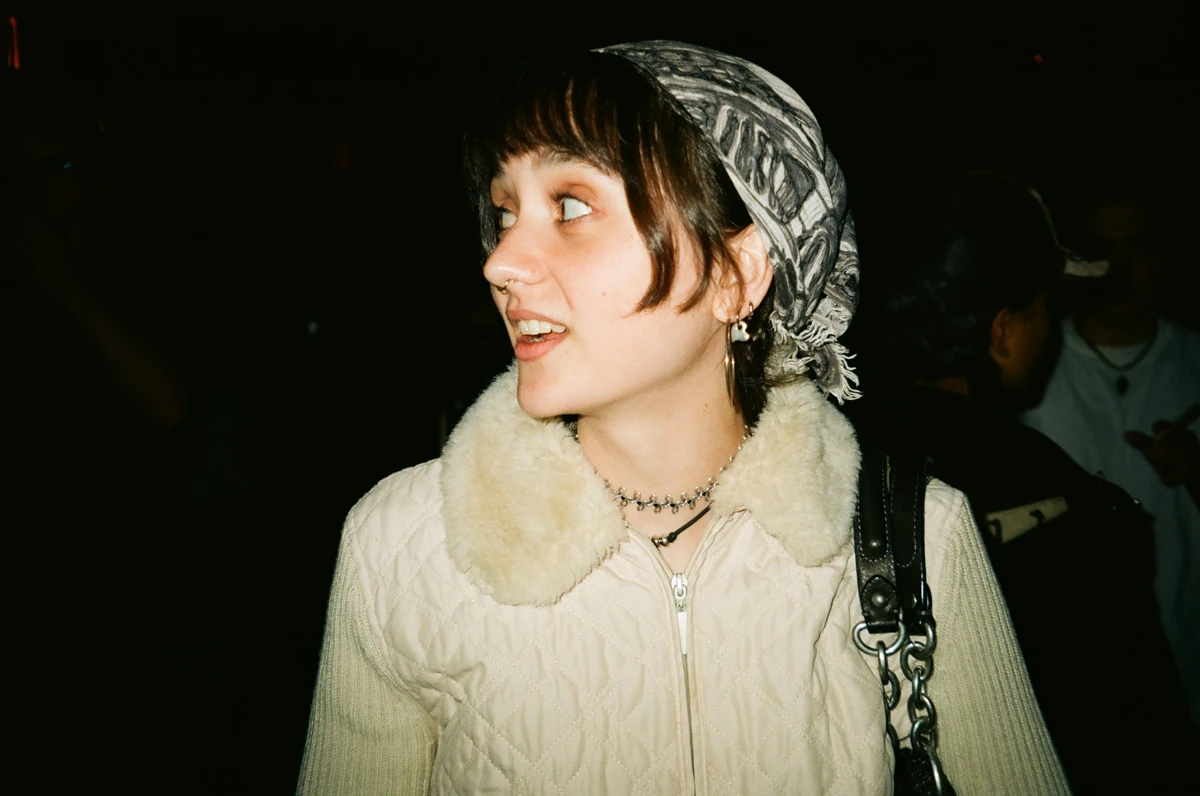 Hannah wearing a patterned headscarf and cream quilted jacket, looking to the side