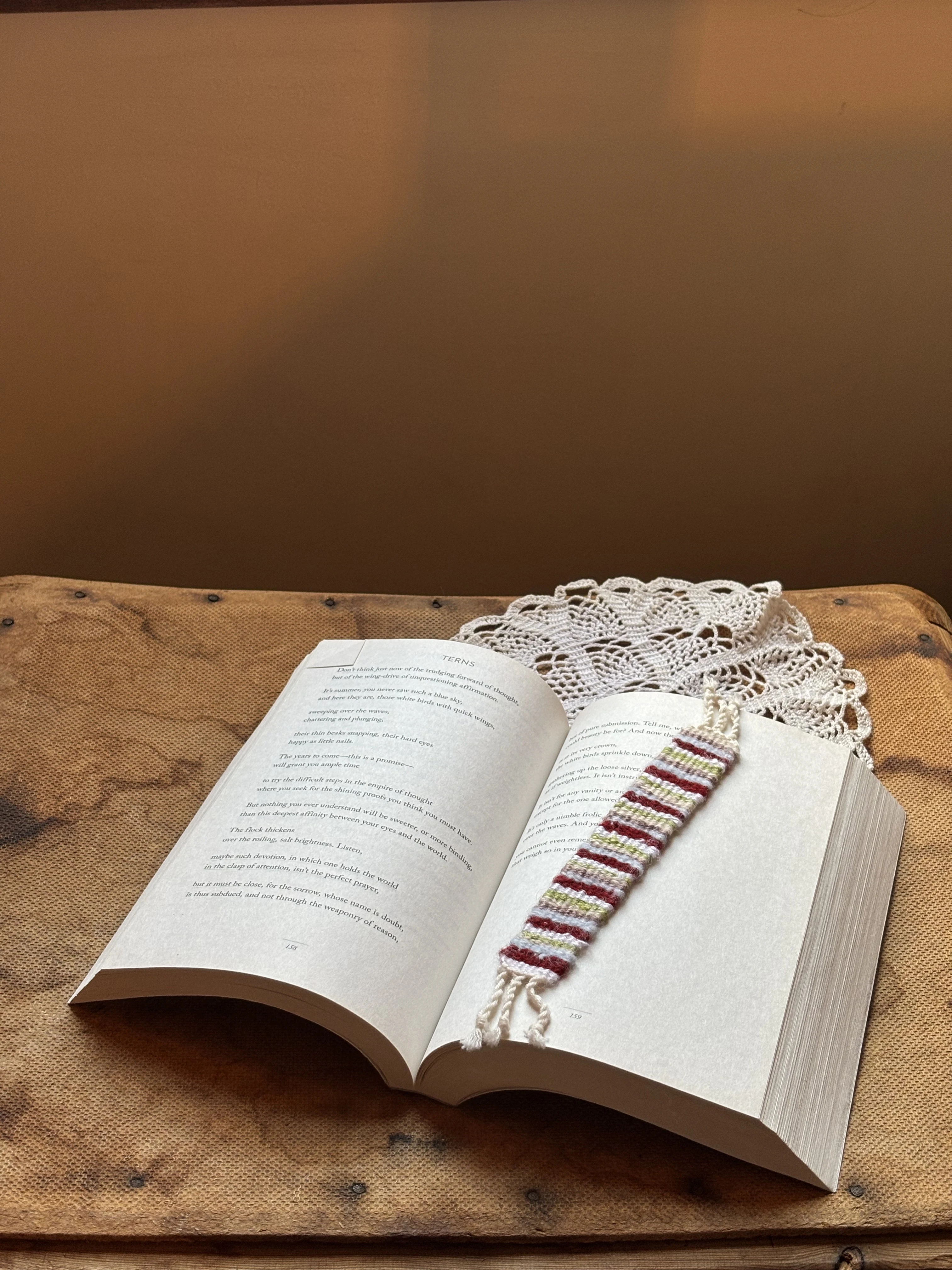 A striped woven bookmark resting in an open book on a wooden chair